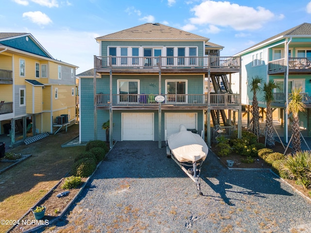 view of front of house featuring central air condition unit, a garage, and a balcony