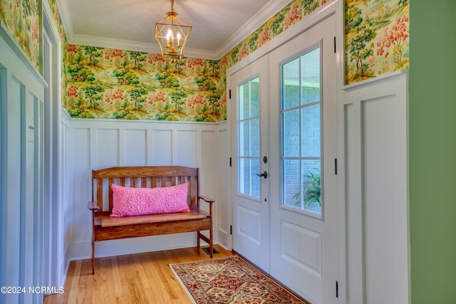 doorway to outside with light hardwood / wood-style floors, an inviting chandelier, and ornamental molding