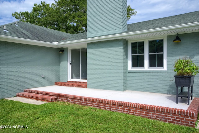 entrance to property featuring a patio area and a lawn