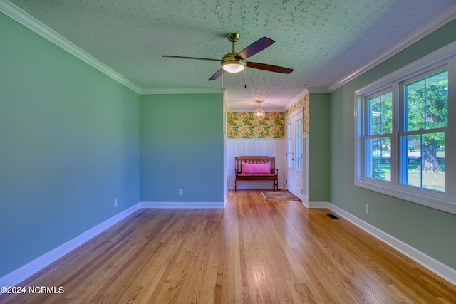 unfurnished room with light hardwood / wood-style floors, a textured ceiling, ceiling fan with notable chandelier, and ornamental molding