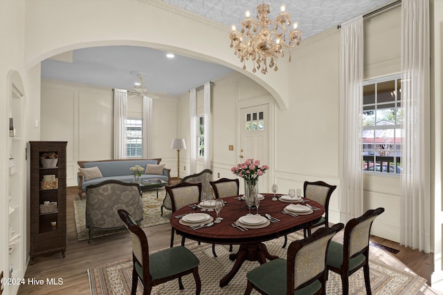 dining space with hardwood / wood-style floors, ceiling fan with notable chandelier, plenty of natural light, and crown molding