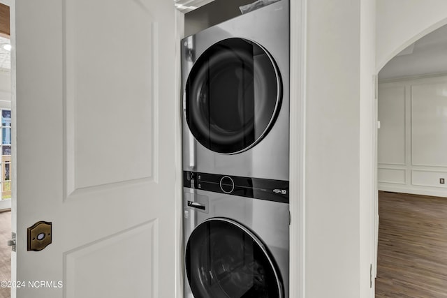 washroom featuring stacked washer and dryer and dark wood-type flooring