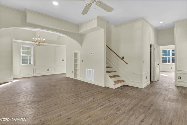 interior space featuring ceiling fan with notable chandelier, wood-type flooring, and ornamental molding