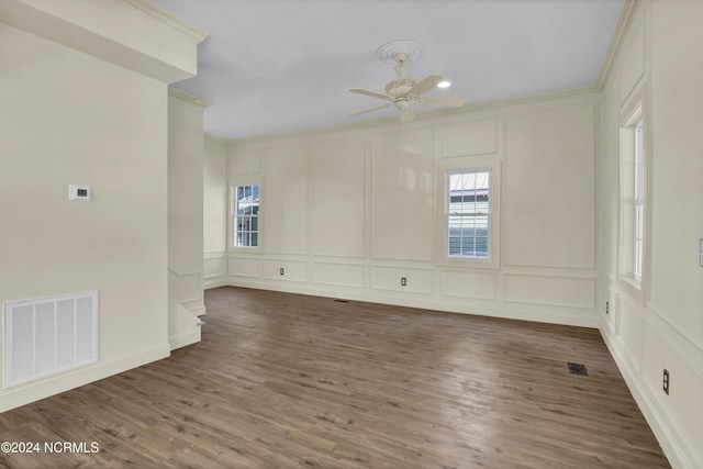 spare room with plenty of natural light, crown molding, and dark wood-type flooring