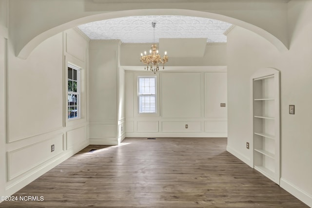 foyer entrance featuring dark hardwood / wood-style flooring, ornamental molding, and an inviting chandelier