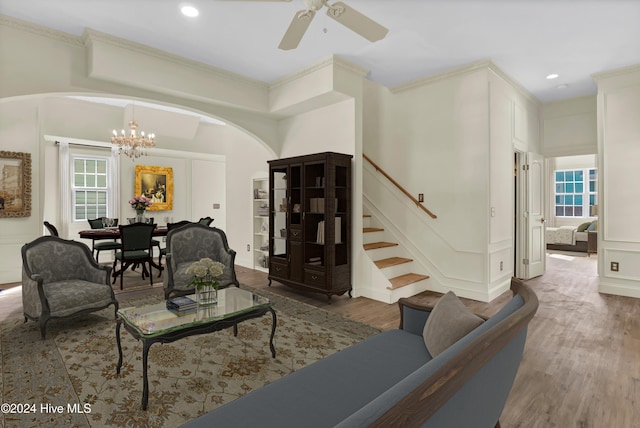 living room with hardwood / wood-style floors, ceiling fan with notable chandelier, and ornamental molding