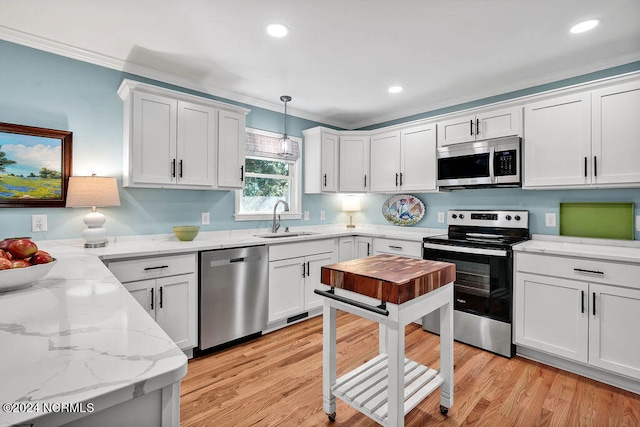 kitchen with light hardwood / wood-style flooring, stainless steel appliances, sink, pendant lighting, and white cabinetry