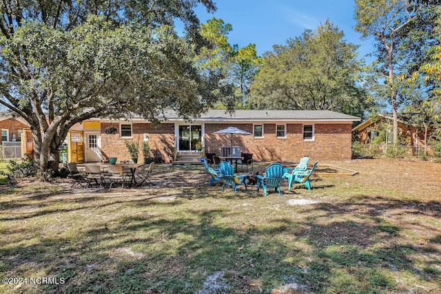 rear view of house with a yard, a patio area, and an outdoor fire pit