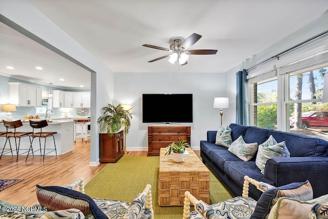 living room featuring ceiling fan, sink, and light wood-type flooring