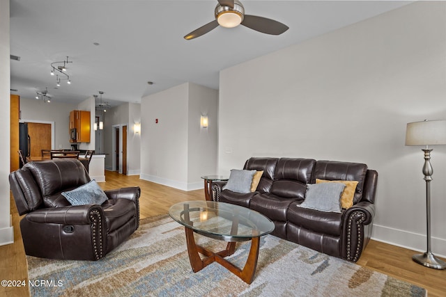 living area featuring ceiling fan, light wood-style flooring, and baseboards