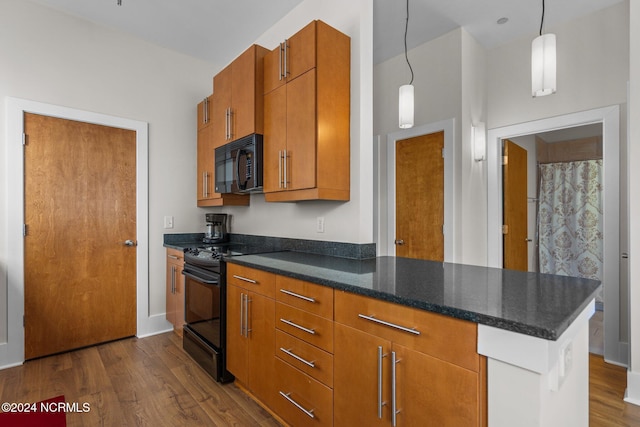 kitchen featuring dark wood-type flooring, dark stone countertops, black appliances, and pendant lighting