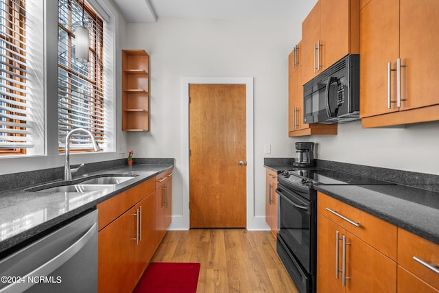 kitchen with dark stone countertops, light hardwood / wood-style flooring, black appliances, and sink