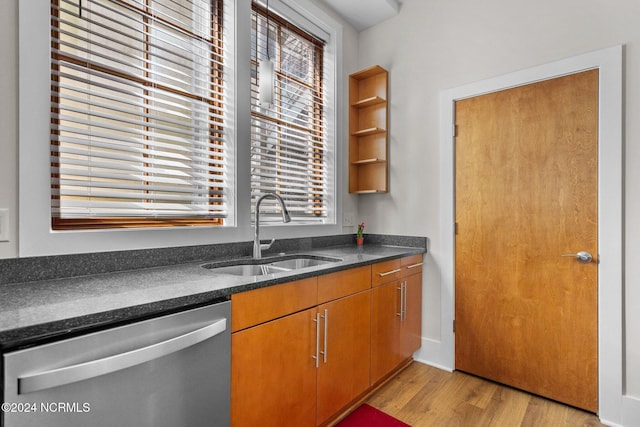 kitchen featuring stainless steel dishwasher, a sink, light wood-type flooring, and brown cabinetry