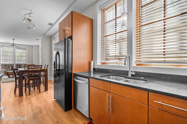 kitchen featuring sink, light wood-type flooring, black fridge, stainless steel dishwasher, and dark stone countertops