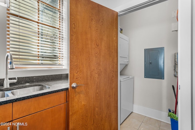 clothes washing area with sink, electric panel, stacked washing maching and dryer, and light tile patterned floors