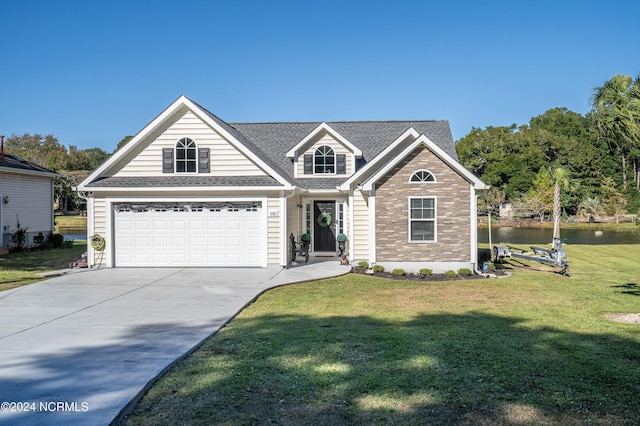 view of front of house with a front yard, a garage, and a water view