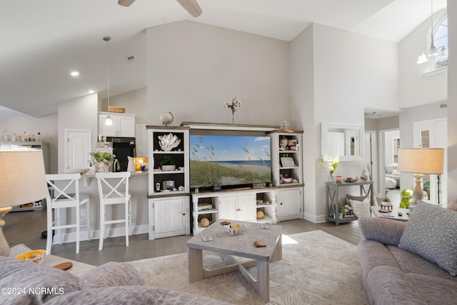 living room with hardwood / wood-style floors, high vaulted ceiling, and ceiling fan