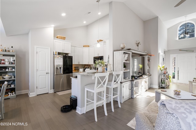 kitchen featuring white cabinets, a breakfast bar, high vaulted ceiling, dark hardwood / wood-style floors, and stainless steel appliances