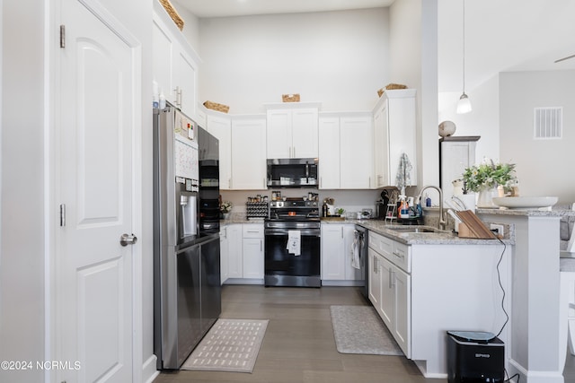 kitchen featuring sink, white cabinetry, stainless steel appliances, pendant lighting, and light stone counters