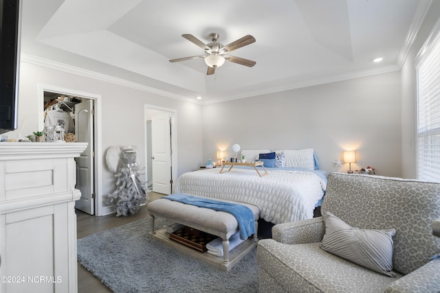 bedroom featuring ornamental molding, hardwood / wood-style flooring, a tray ceiling, and ceiling fan