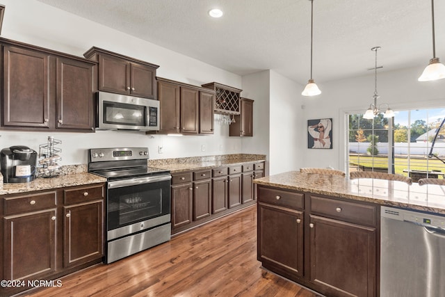 kitchen featuring appliances with stainless steel finishes, dark brown cabinets, hanging light fixtures, a chandelier, and dark hardwood / wood-style floors