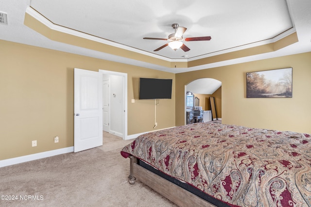 bedroom with ornamental molding, a raised ceiling, light colored carpet, and ceiling fan