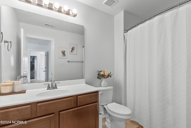 bathroom with vanity, toilet, and a textured ceiling