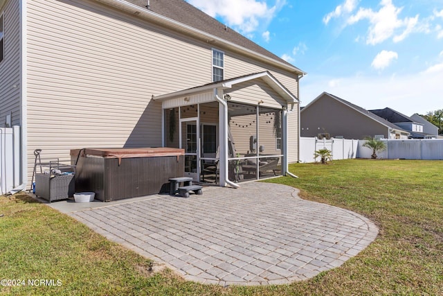 back of property featuring a patio, a hot tub, a sunroom, and a lawn