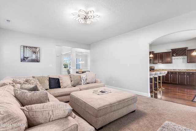 living room with a textured ceiling, an inviting chandelier, and dark hardwood / wood-style flooring