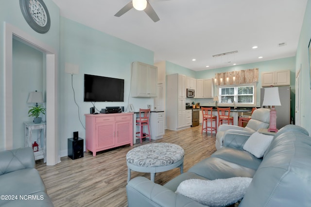 living room with light hardwood / wood-style flooring and ceiling fan