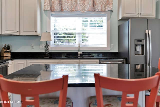 kitchen featuring dark stone countertops, white cabinetry, sink, and appliances with stainless steel finishes