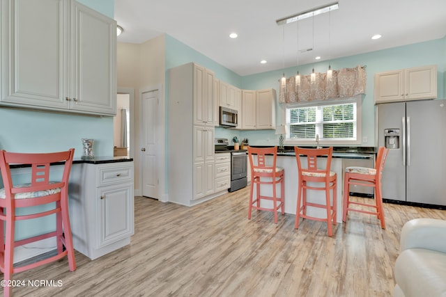 kitchen with a center island, light wood-type flooring, a breakfast bar area, and appliances with stainless steel finishes