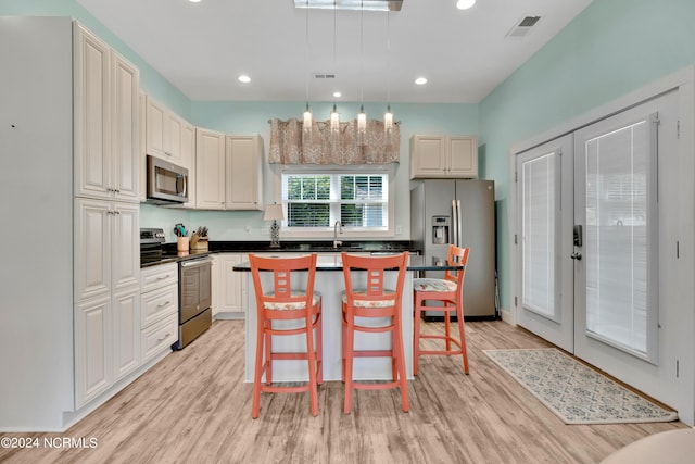 kitchen with a center island, a kitchen bar, stainless steel appliances, and light hardwood / wood-style flooring