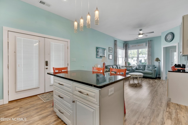 kitchen with light hardwood / wood-style flooring, ceiling fan, decorative light fixtures, a kitchen island, and white cabinetry