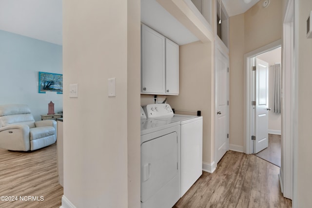 laundry area featuring washer and clothes dryer, cabinets, and light wood-type flooring