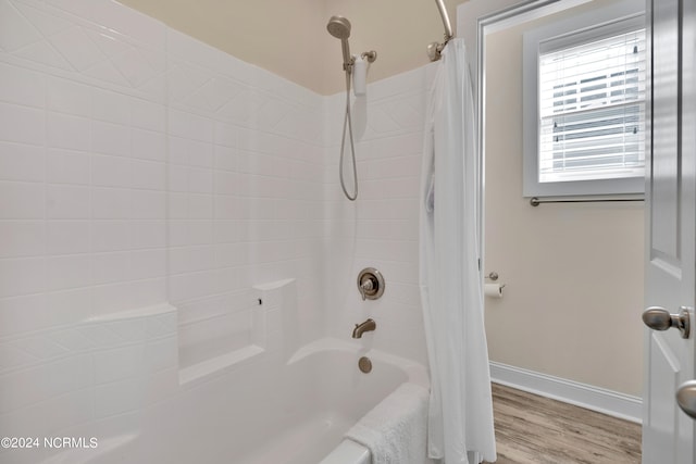 bathroom with hardwood / wood-style flooring and shower / bath combo with shower curtain