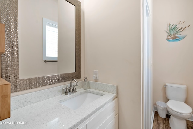 bathroom with hardwood / wood-style floors, vanity, and toilet