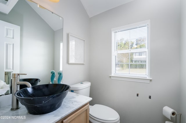 bathroom featuring vanity, lofted ceiling, and toilet