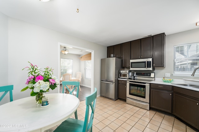 kitchen featuring dark brown cabinetry, stainless steel appliances, sink, and light tile patterned floors