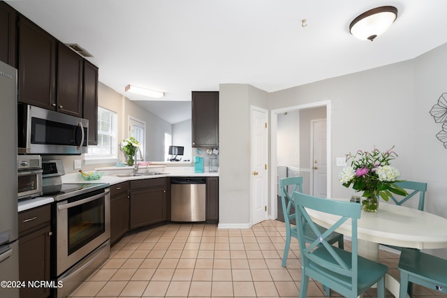 kitchen featuring stainless steel appliances, dark brown cabinetry, sink, and light tile patterned flooring