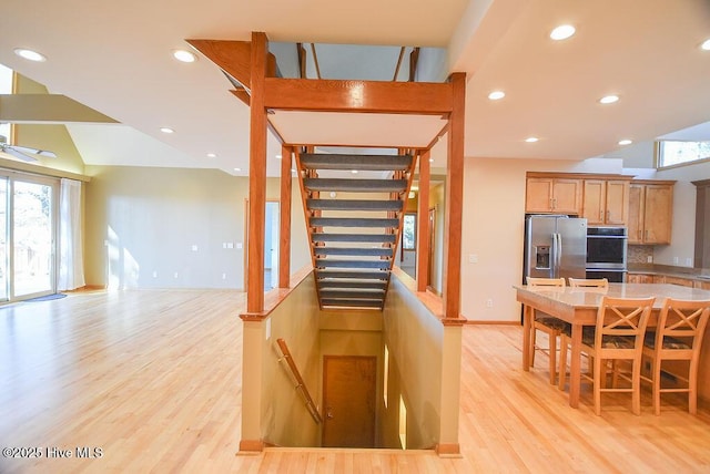 kitchen featuring stainless steel appliances, vaulted ceiling, light wood-type flooring, and plenty of natural light