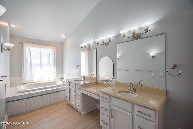 bathroom featuring a relaxing tiled tub, lofted ceiling, vanity, and hardwood / wood-style flooring