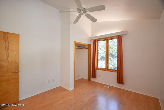 unfurnished bedroom with ceiling fan, light wood-type flooring, a closet, and lofted ceiling