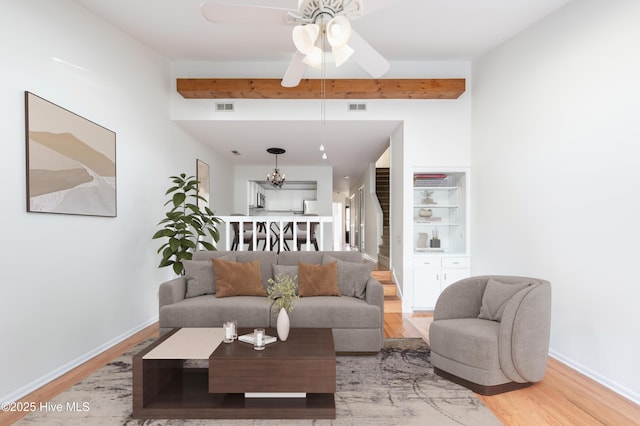 living area with visible vents, light wood finished floors, and beamed ceiling