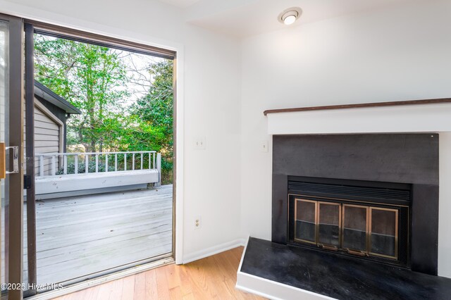 room details with a glass covered fireplace, baseboards, and wood finished floors