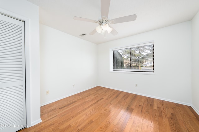 empty room with light wood finished floors, baseboards, a ceiling fan, and visible vents