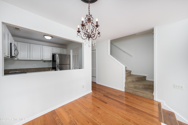 kitchen featuring decorative light fixtures, light wood finished floors, stainless steel appliances, visible vents, and baseboards