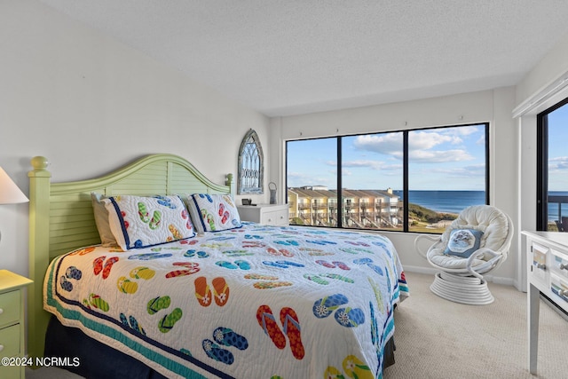 carpeted bedroom with a textured ceiling and a water view