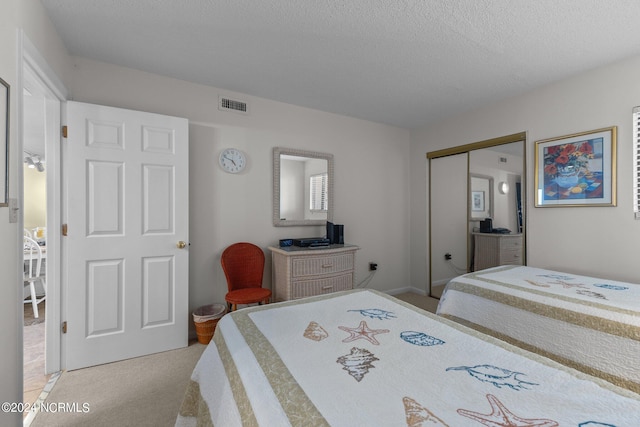 bedroom featuring a closet, a textured ceiling, and light colored carpet