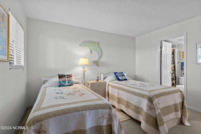 carpeted bedroom featuring ensuite bathroom and a textured ceiling